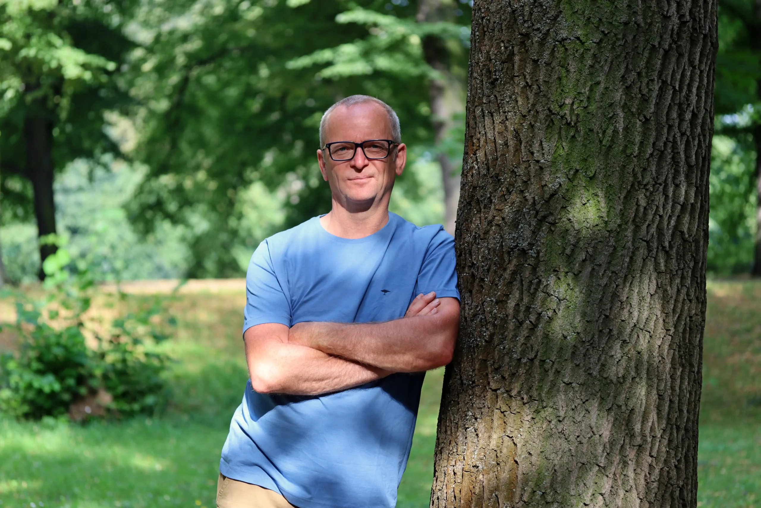 Eckart Julitz steht an einem Baum in einer grünen Park- oder Waldumgebung in Leipzig.